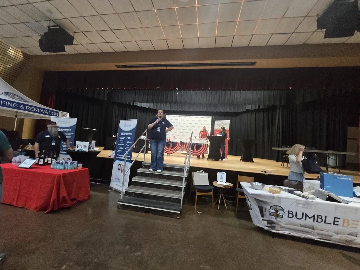 Business expo hall with vendor booths, a stage and attendees