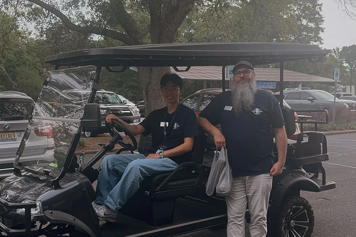 Southern View Media team members beside a golf cart at an outdoor event